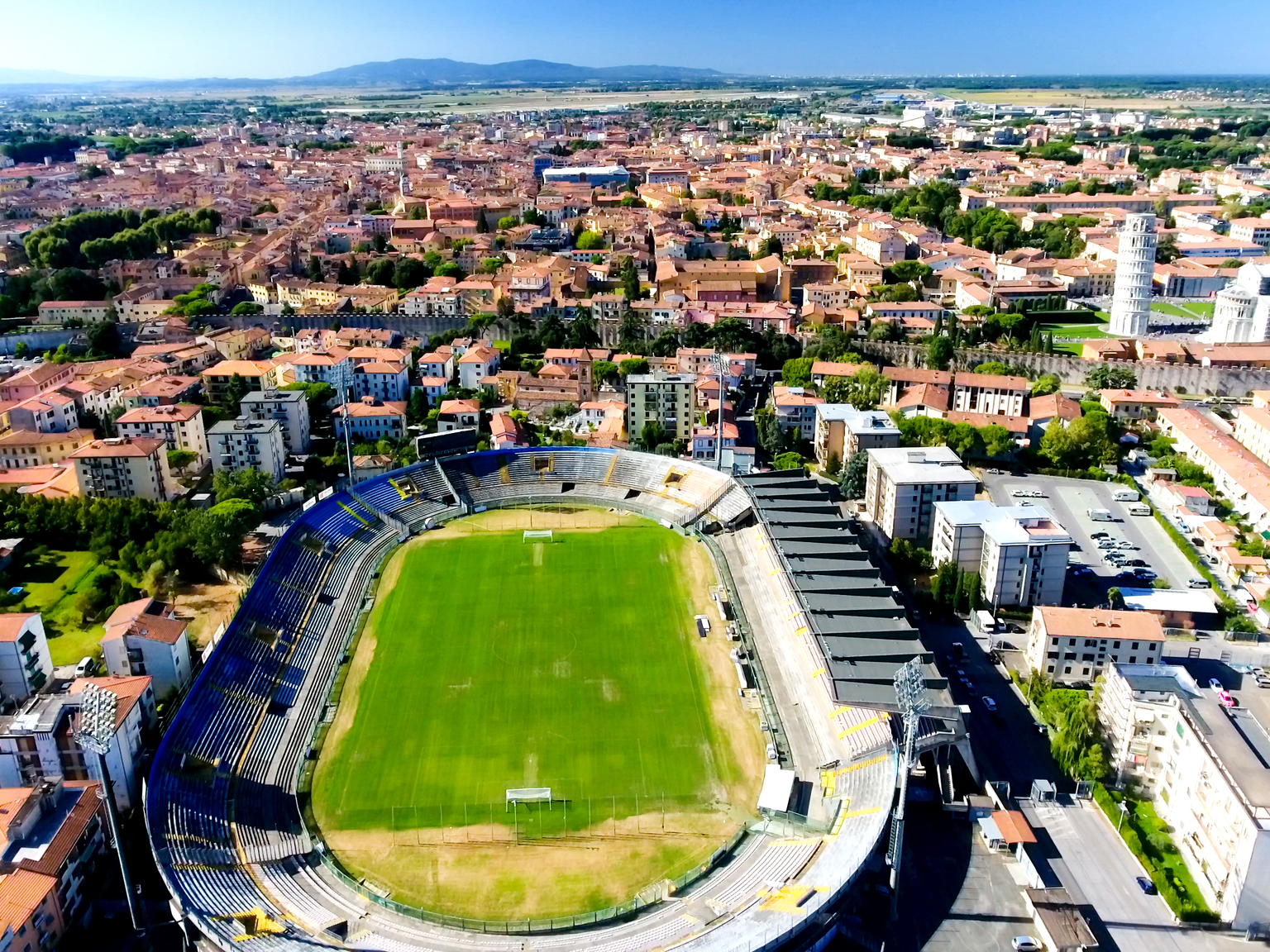 Aerial view of a city featuring a stadium and the Leaning Tower of Pisa.