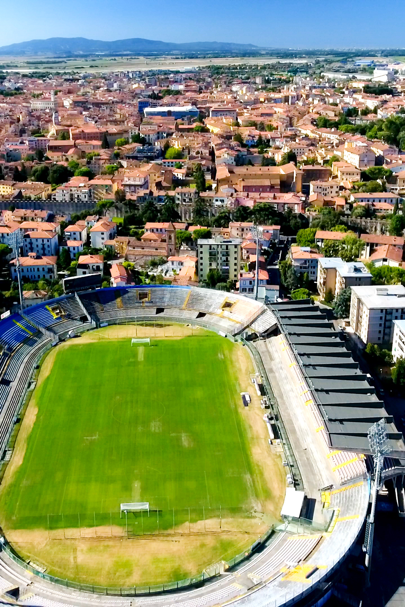 Aerial view of a city featuring a stadium and the Leaning Tower of Pisa.