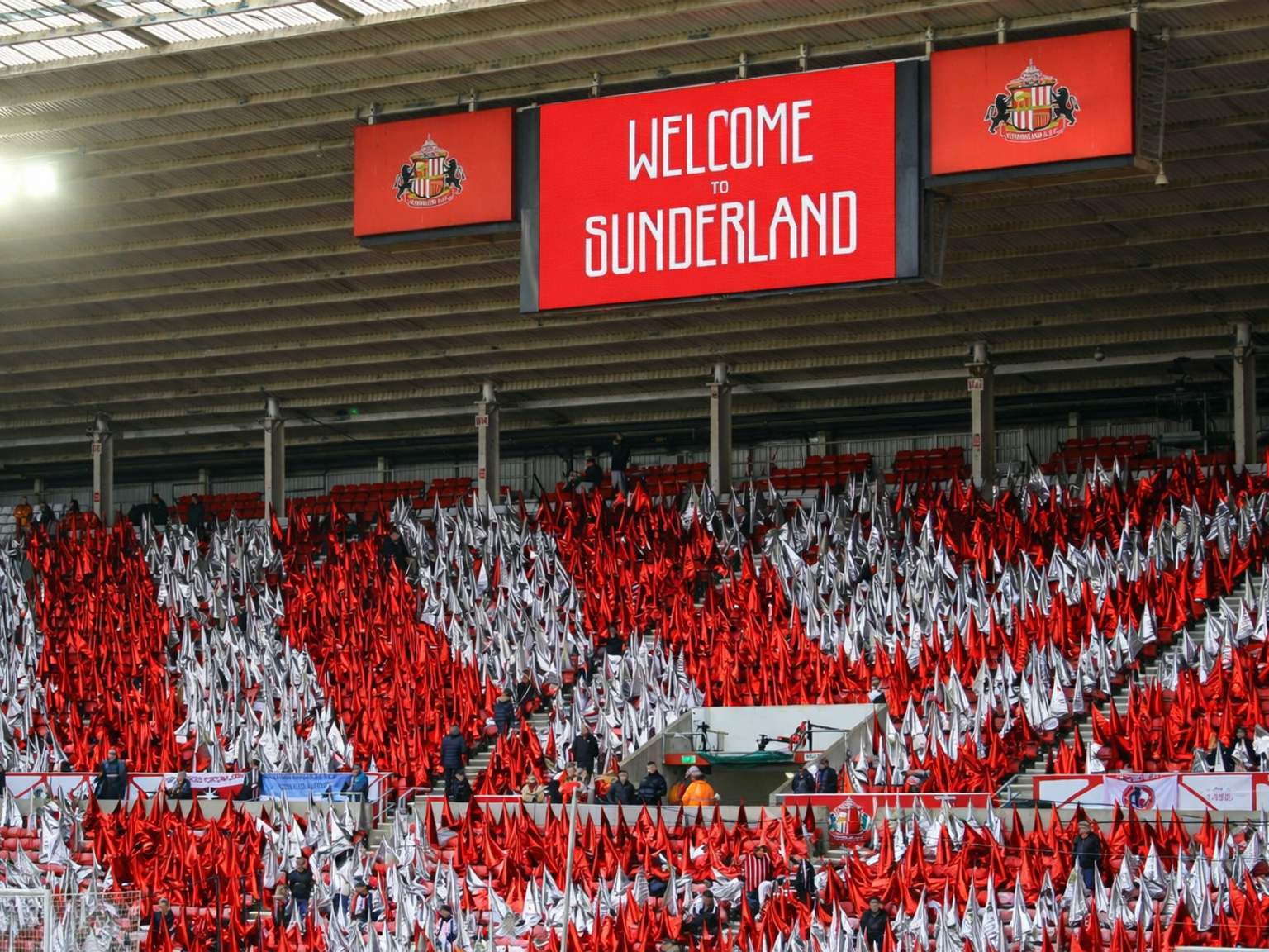 Red and white flags fill the stadium stands, with screens above reading "WELCOME TO SUNDERLAND."