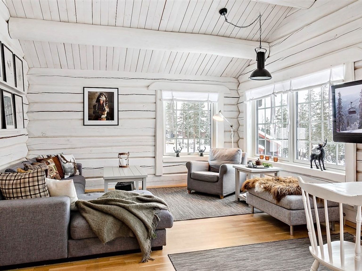 en stue i en bjælkehytte med en sofa, stol, bord og fjernsyn.