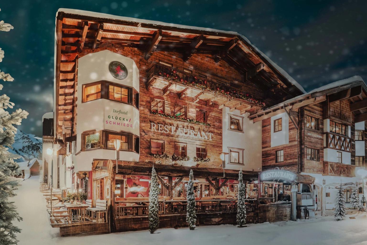 een groot houten gebouw is 's nachts bedekt met sneeuw, Hotel Gluecksschmiede, Saalbach-Hinterglemm