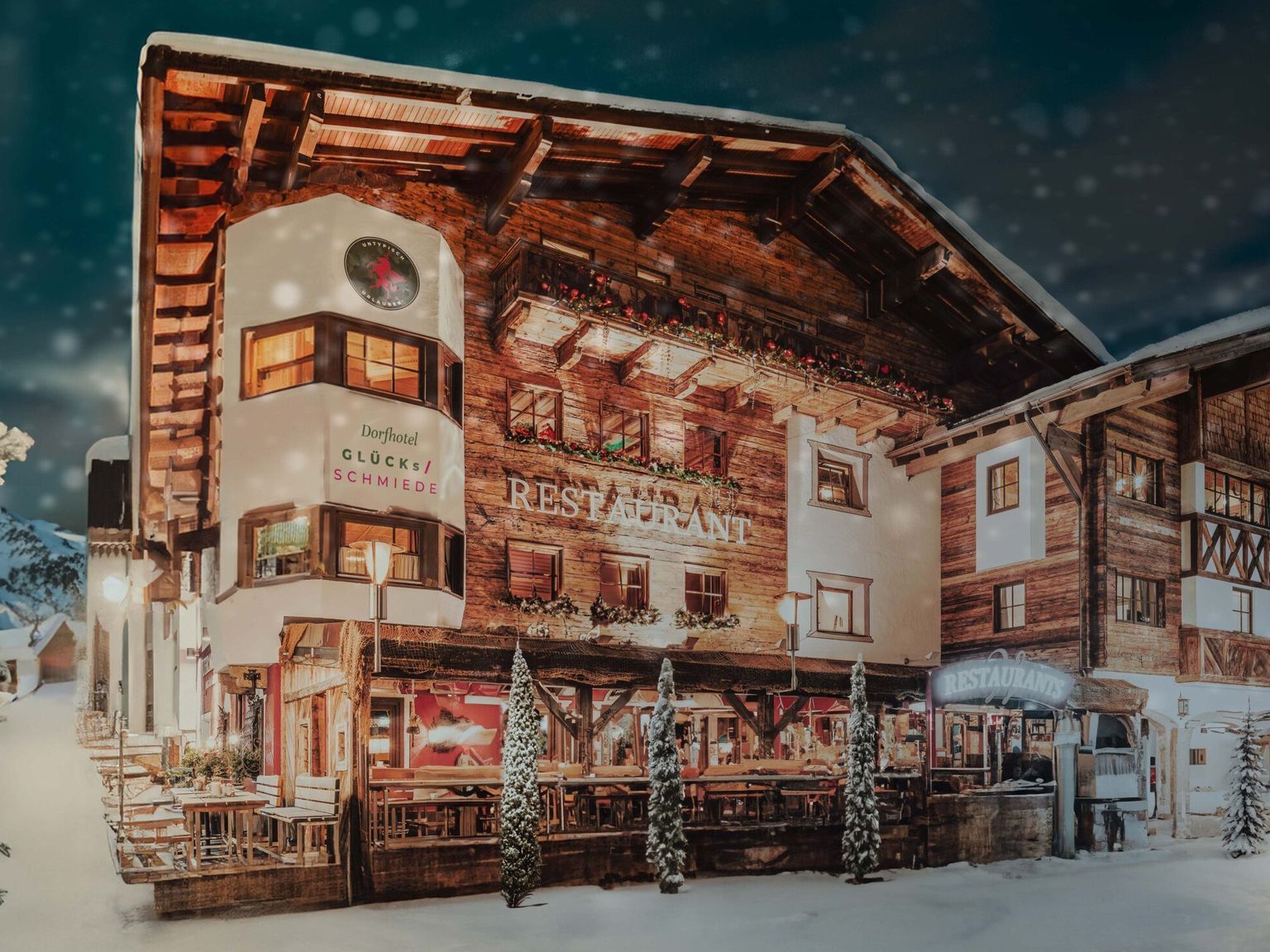een groot houten gebouw is 's nachts bedekt met sneeuw, Hotel Gluecksschmiede, Saalbach-Hinterglemm