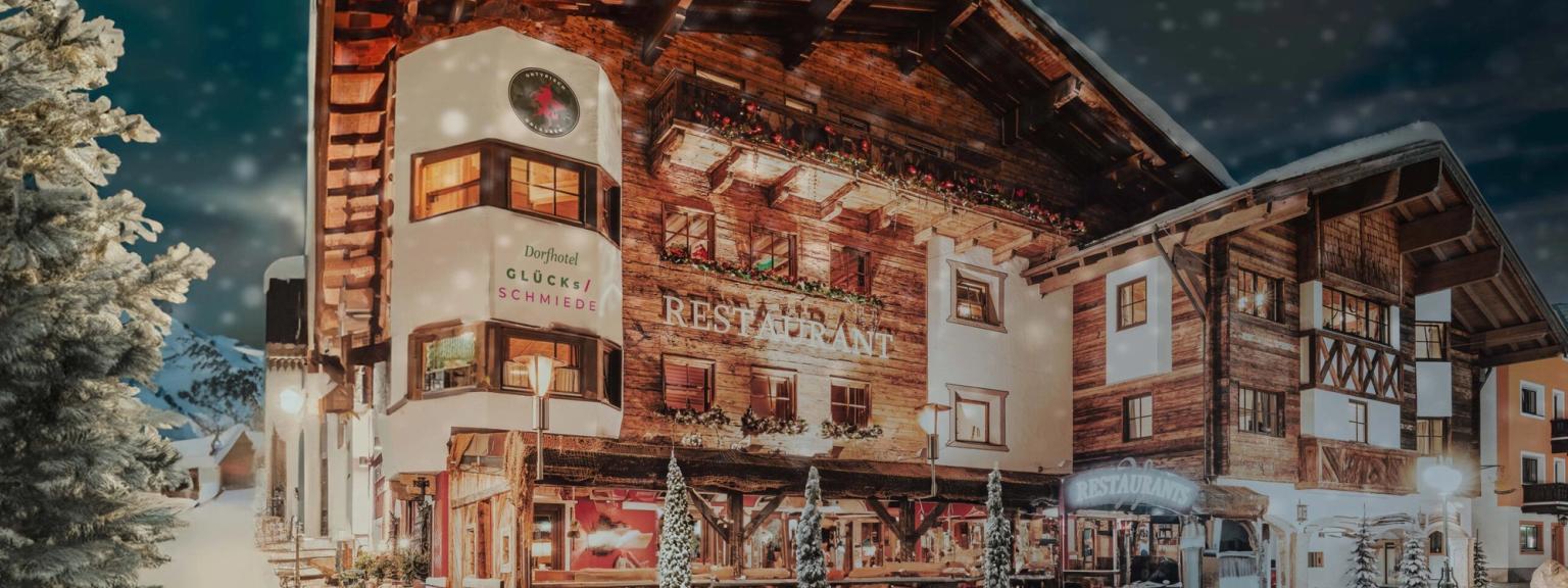 en stor trebygning er dekket av snø om natten, Hotel Gluecksschmiede, Saalbach-Hinterglemm
