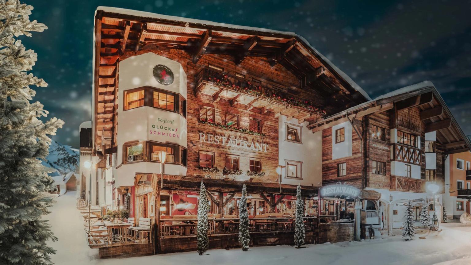 een groot houten gebouw is 's nachts bedekt met sneeuw, Hotel Gluecksschmiede, Saalbach-Hinterglemm