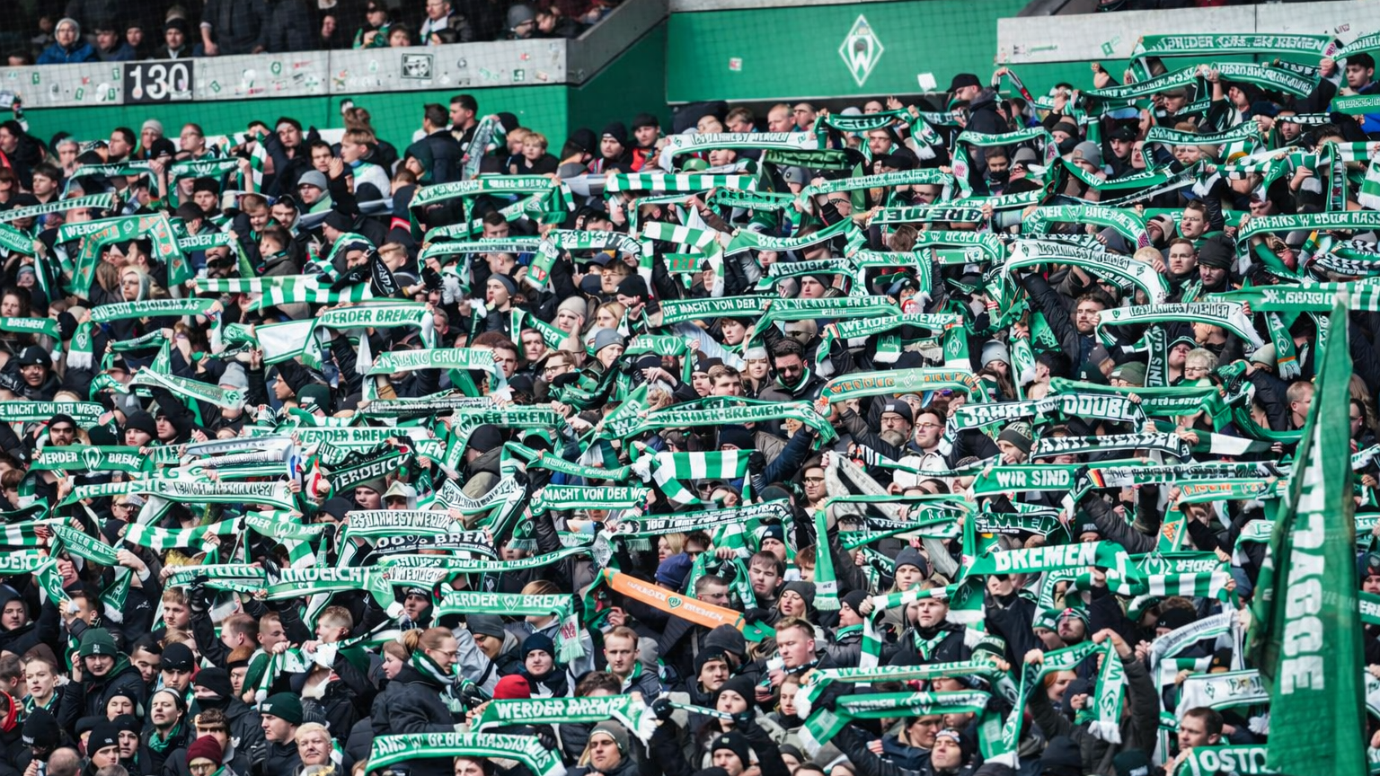 Fans på et stadion som holder grønne og hvite skjerf.