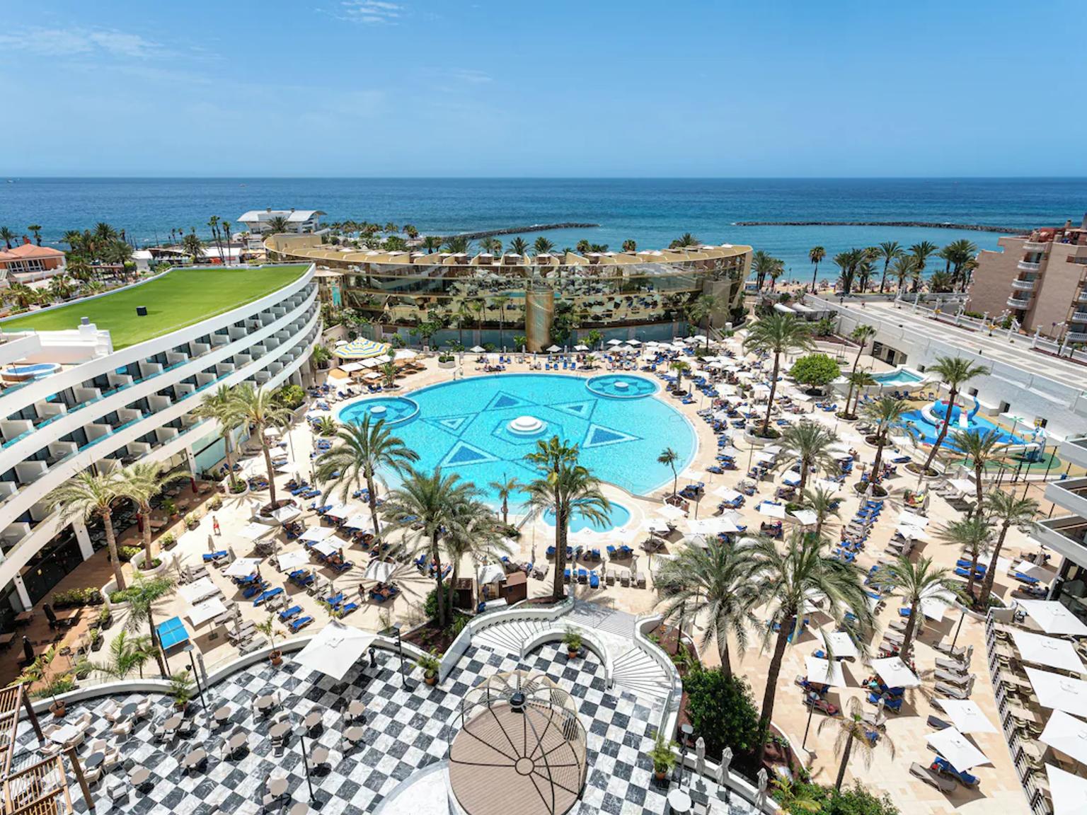 et luftfoto af et stort hotel med en stor pool omgivet af palmer.