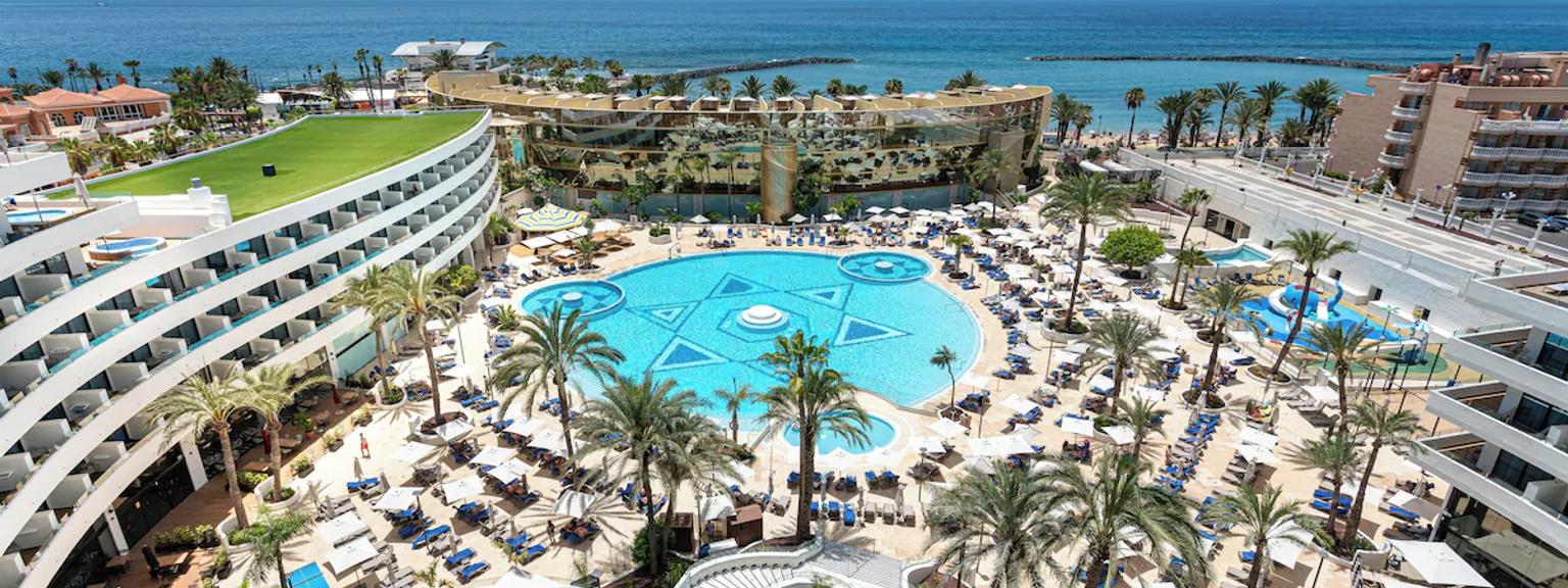 et luftfoto af et stort hotel med en stor pool omgivet af palmer.