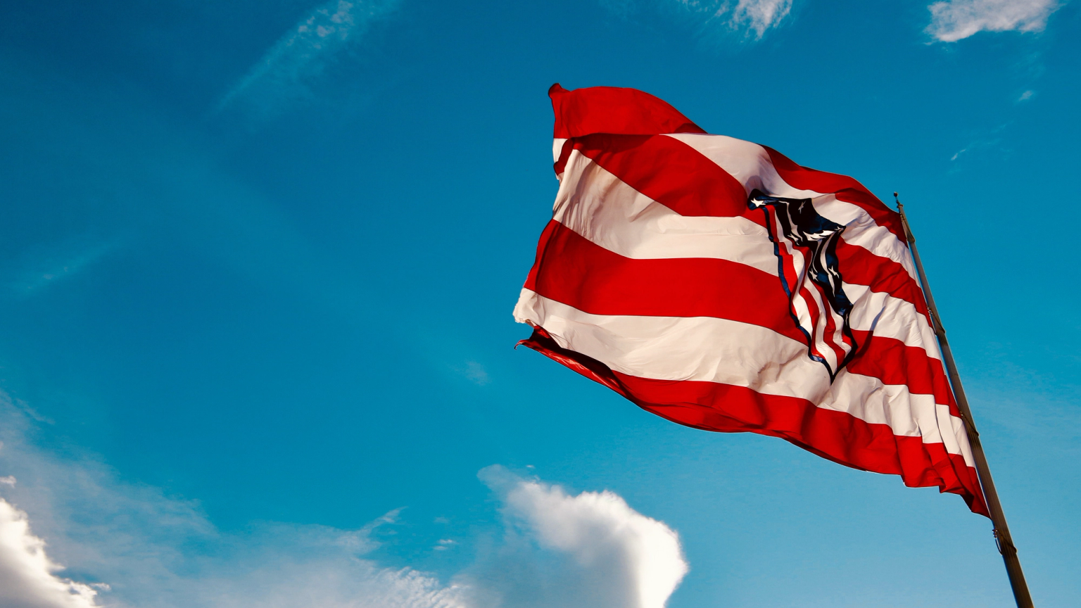 Atlético Madrid flag with red and white stripes waving against a bright blue sky.