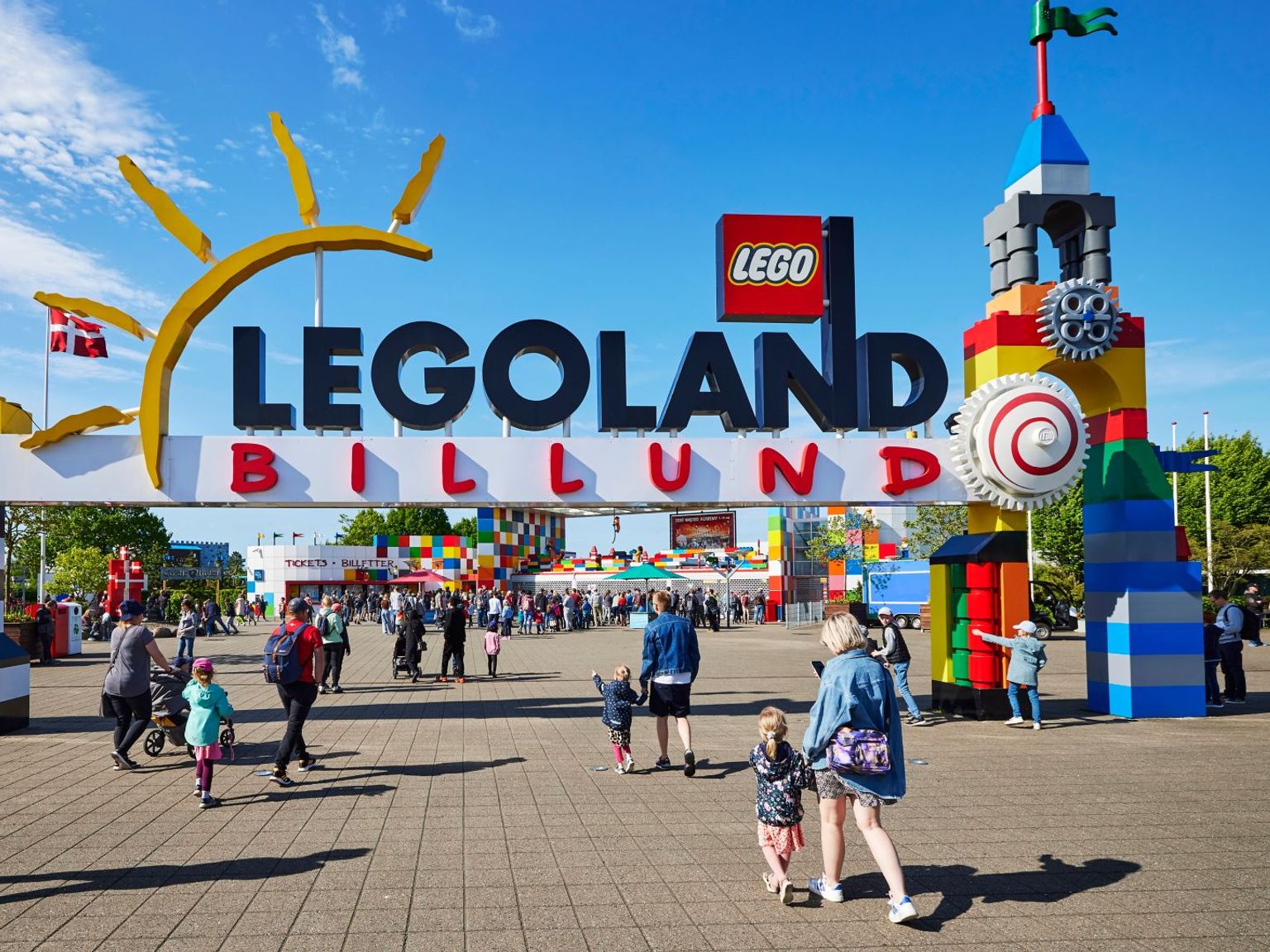 en grupp människor går under en skylt som säger legoland billund.