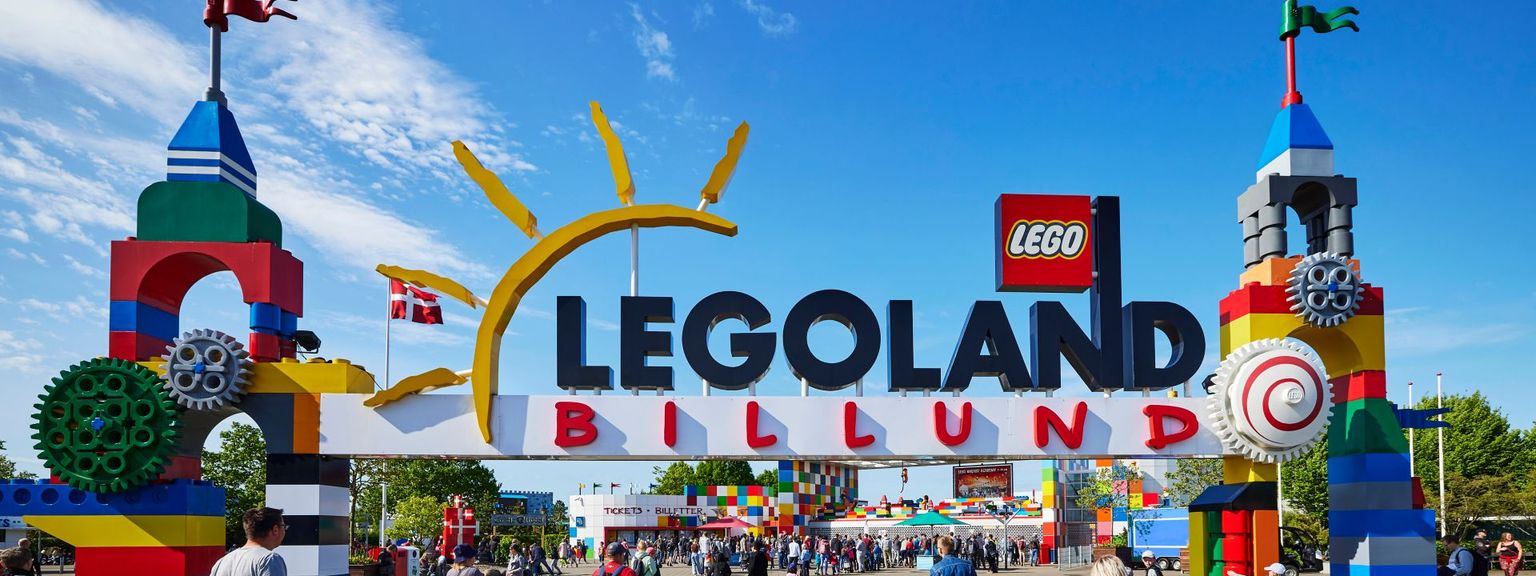 en grupp människor går under en skylt som säger legoland billund.