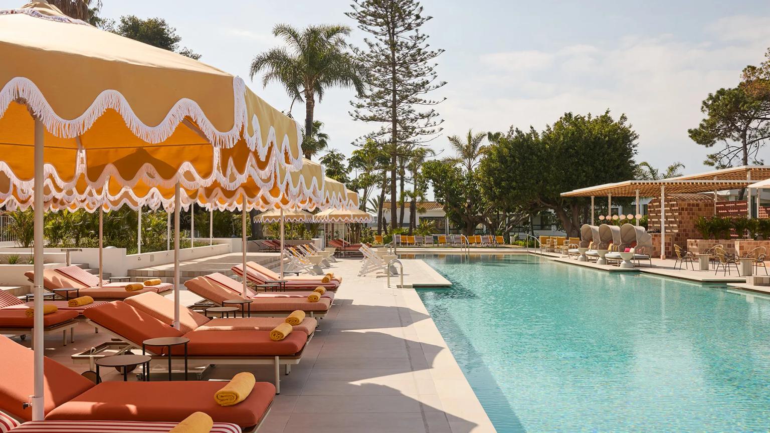 et stort svømmebasseng omgitt av solsenger og parasoller