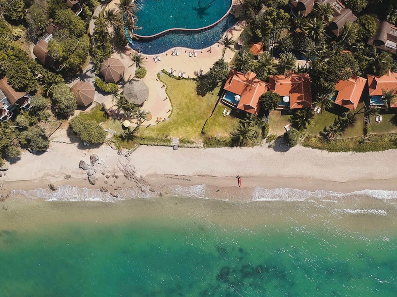 eine Luftaufnahme eines Strandes mit einem Schwimmbad und Häusern