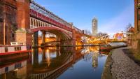 a bridge over a river with a building in the background at night