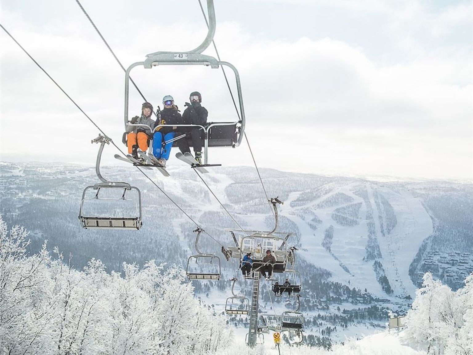 en gruppe mennesker kører på en skilift op ad et sneklædt bjerg