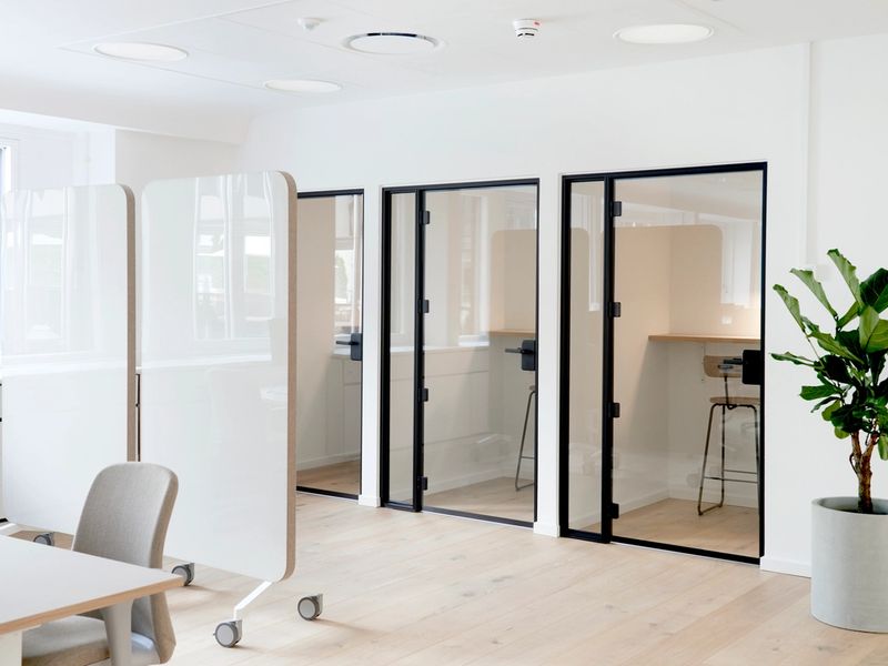 A modern office interior with a row of sleek, glass-walled phone booths for private calls.