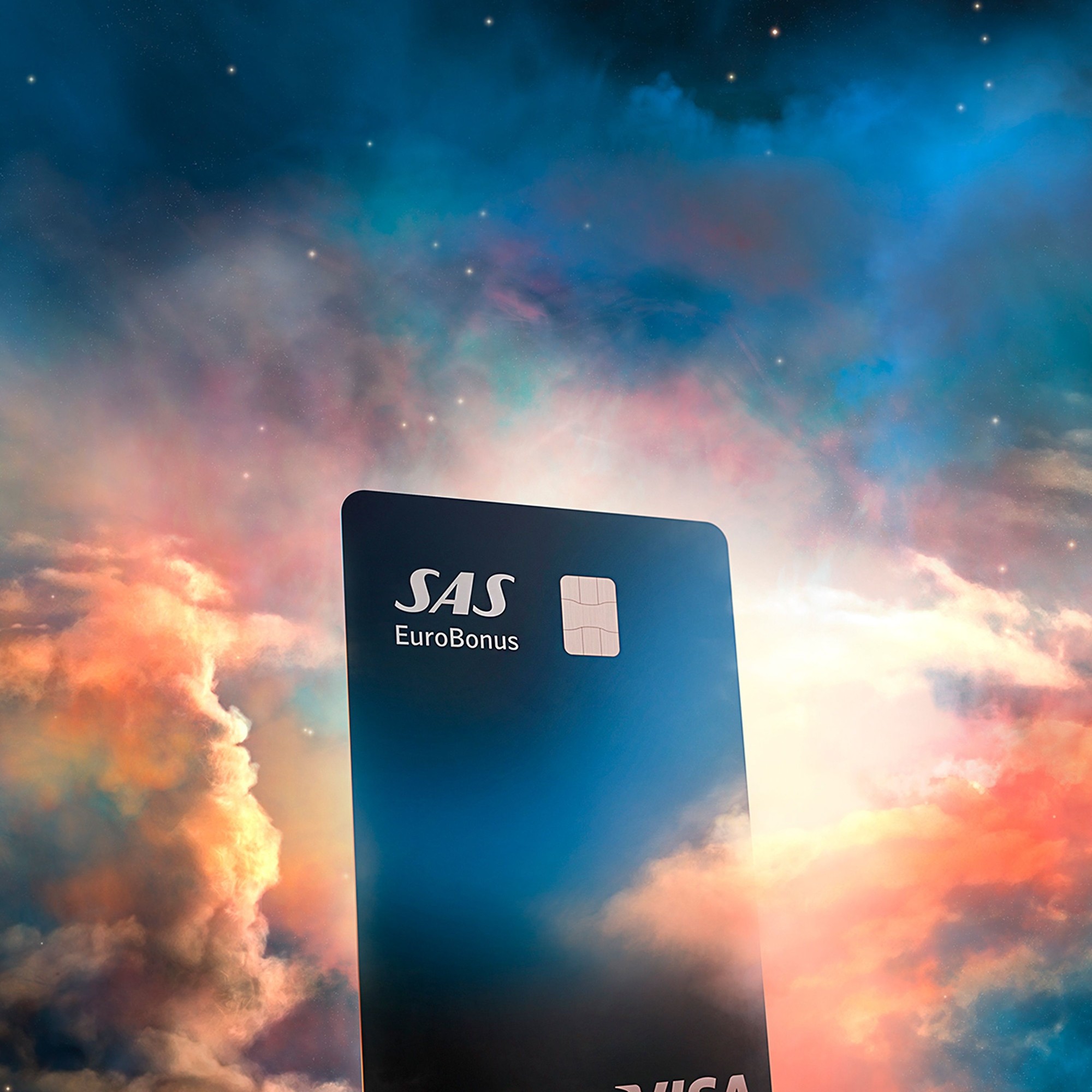 Et Lunar SAS EuroBonus Visa-kort, der svæver blandt farverige, drømmeagtige skyer under en stjerneklar nattehimmel.