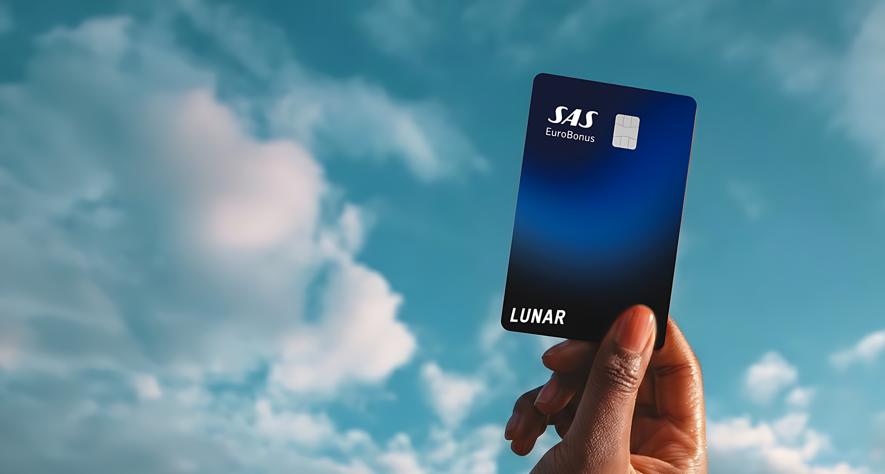Lunar SAS EuroBonus Visa-kortet, der svæver horisontalt blandt farverige, drømmeagtige skyer under en stjernehimmel.