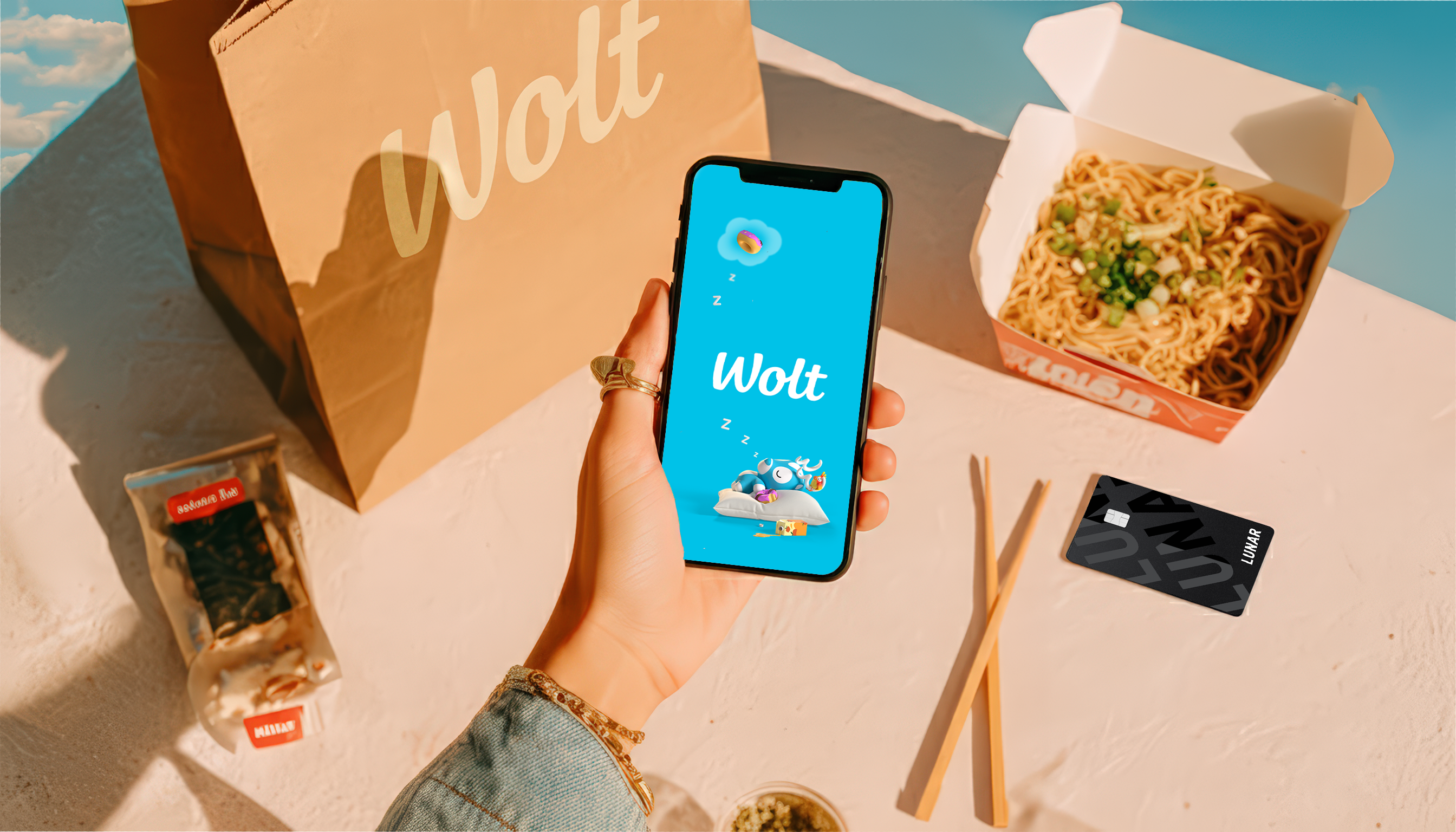 En person står i en mataffär och håller i en återanvändbar nätkasse fylld med färska grönsaker som purjolök och bladgrönsaker.