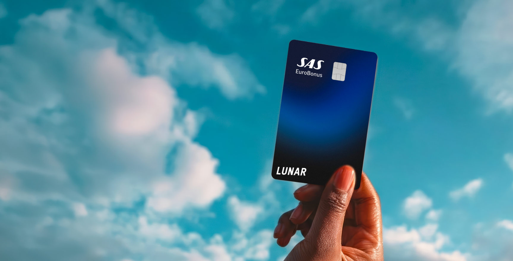 Lunar SAS EuroBonus Visa-kortet, der svæver horisontalt blandt farverige, drømmeagtige skyer under en stjernehimmel.