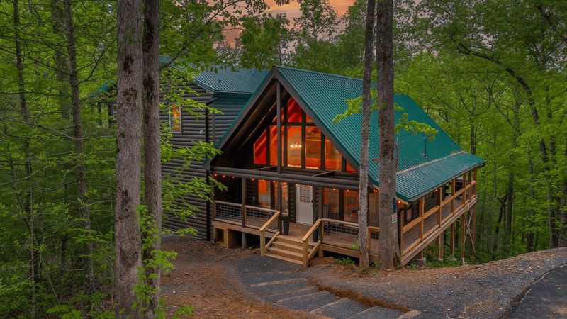 Stairs leading down to a large cabin in the woods. The cabin has large windows at the front of the property.
