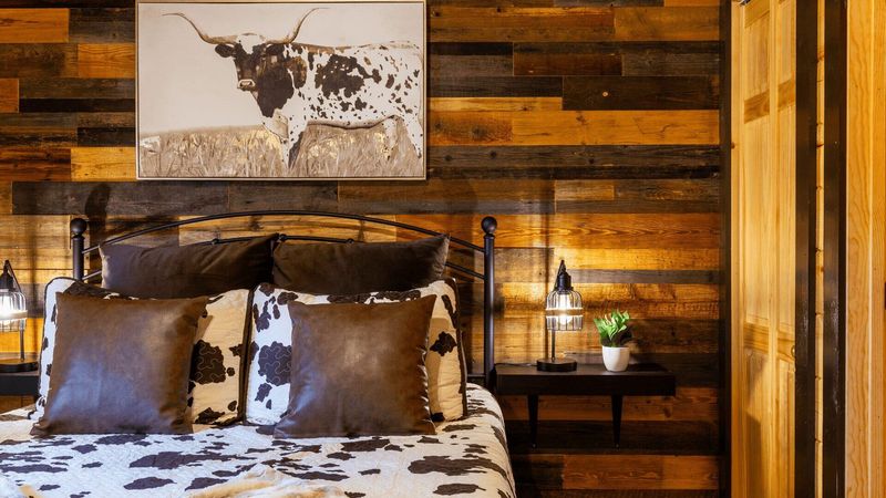 A double bed, with a cow pattern bedsheet. A painting of a cow hangs above the bed.