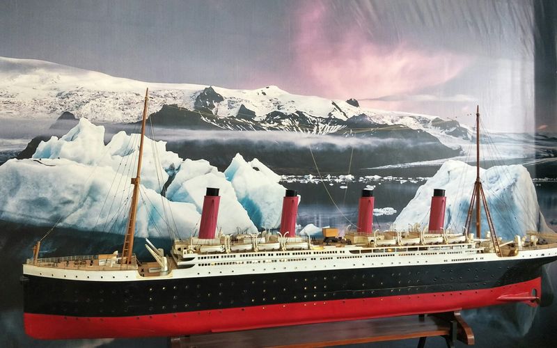 A large model of the Titanic ship is displayed at this popular Pigeon Forge attraction, set against a backdrop of icy waters, icebergs, and snow-covered mountains beneath a pink and purple sky—perfect for fans of the Titanic Museum.