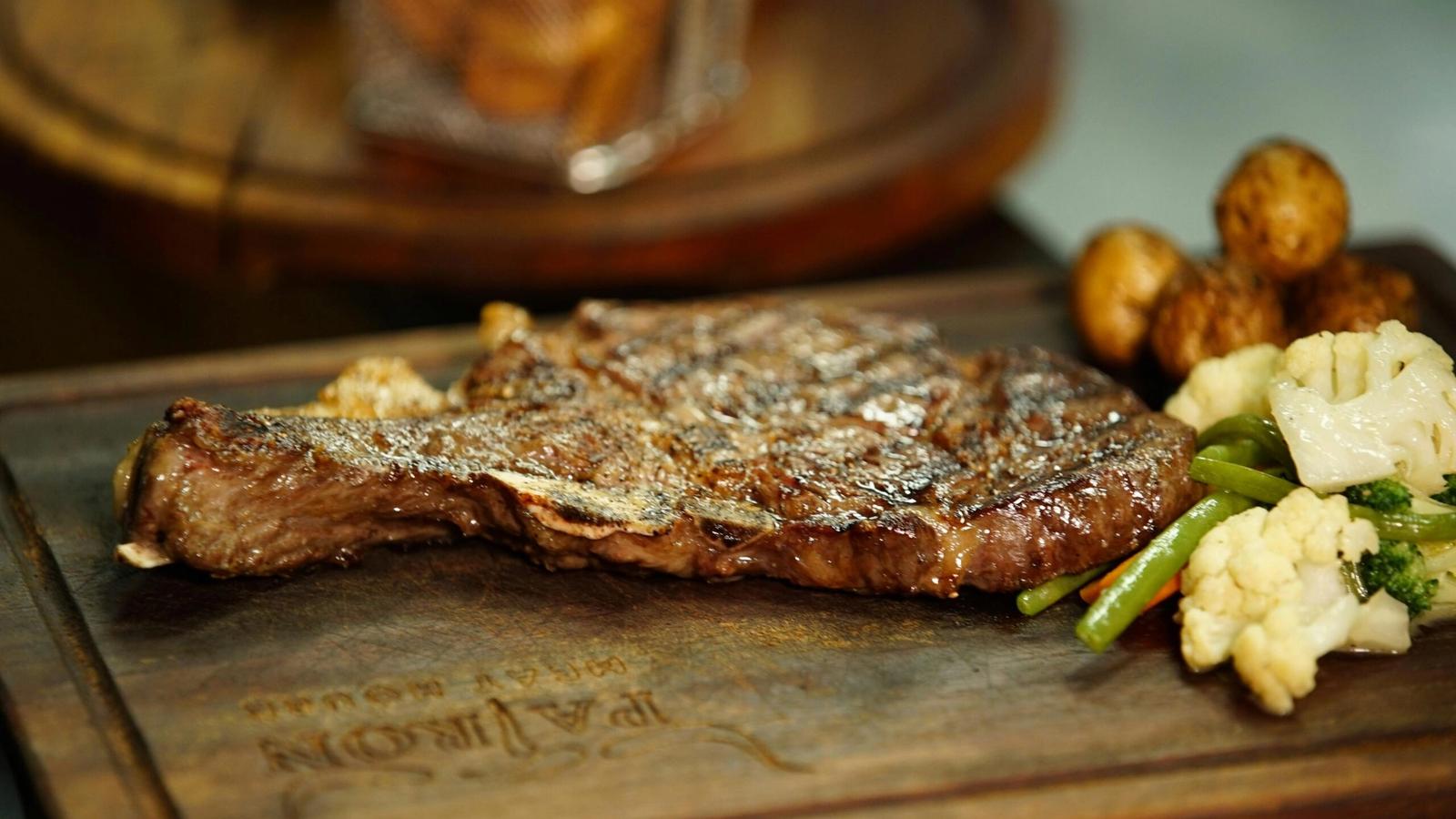A grilled steak served on a wooden board with a side of mixed vegetables, including green beans, cauliflower, and mushrooms—just one highlight from the Cherokee Grill menu in Gatlinburg TN.