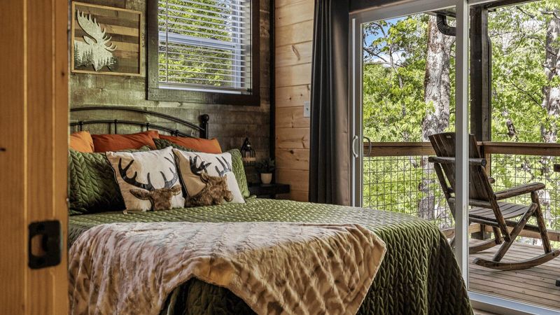 A bed next to a sliding door. There is a balcony with a wooden rocking chair.