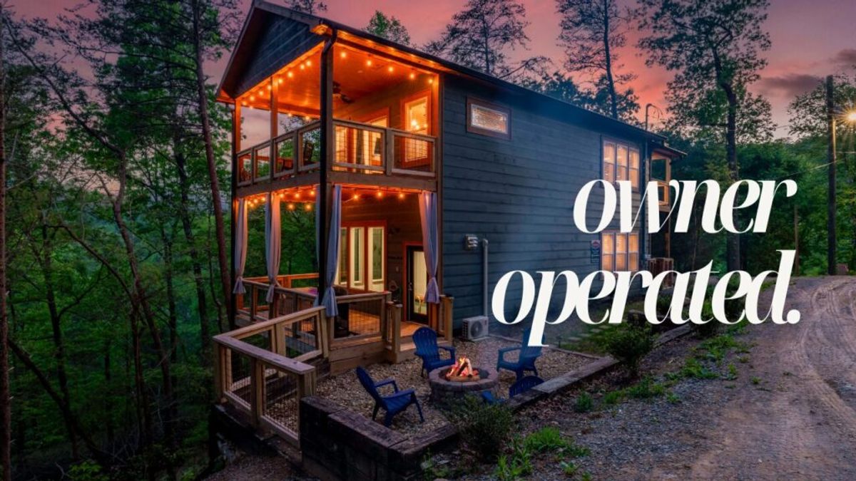 A cozy, two-story cabin with string lights on the porch sits in a wooded area at sunset, featuring a fire pit and blue chairs outside. Large white text reads, “owner operated—Why We Stand Out.”.