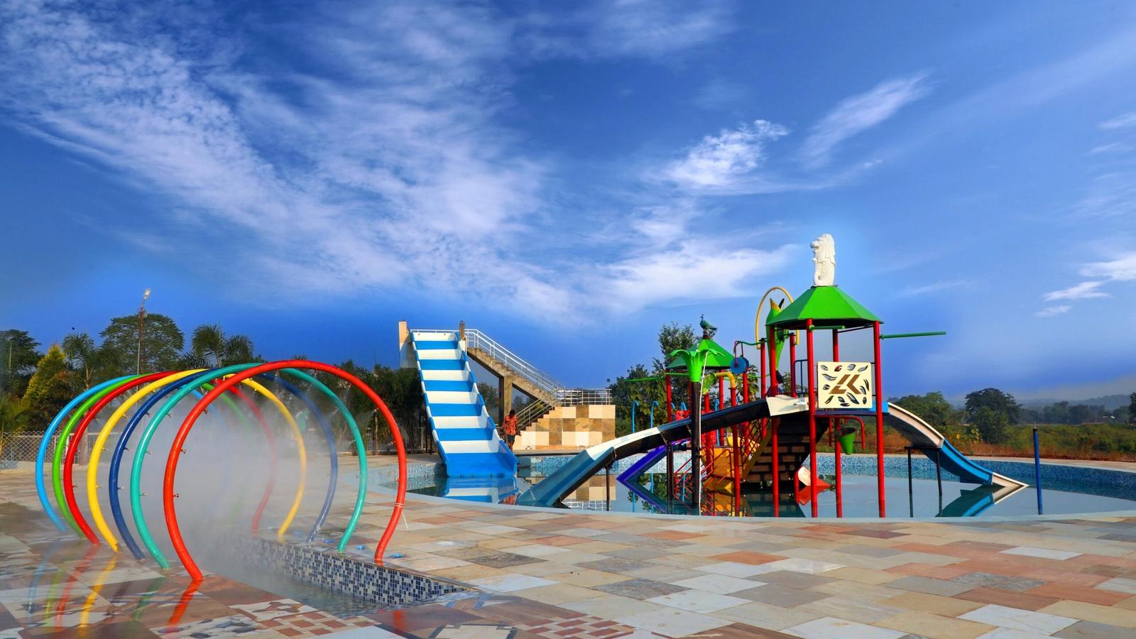 A colorful outdoor water playground at Soaky Mountain Waterpark features slides, climbing structures, and water spray arches under a bright blue sky, with tiled flooring and greenery—perfect for any travel guide.