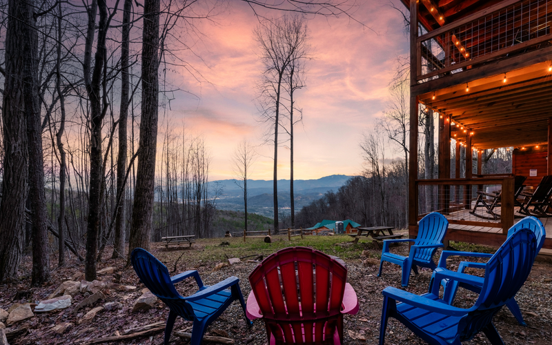 Colorful outdoor fire pit area chairs, overlooking a mountain view at sunset.