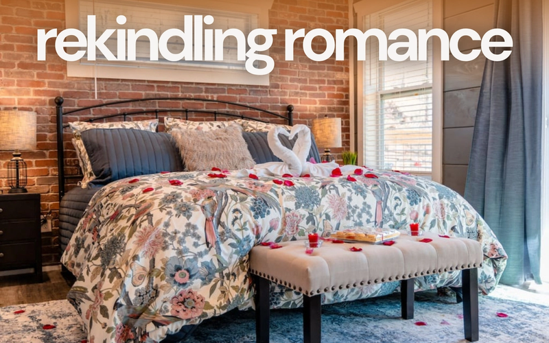 A cozy bedroom with a floral bedspread, swan towels, and rose petals on the bed sets the scene for a couples retreat. Warm lighting and brick walls create a romantic atmosphere, with "rekindling romance" in large white text above.