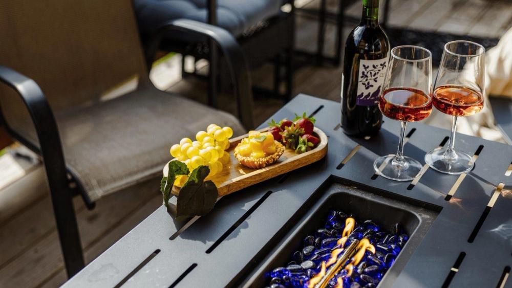 A bottle of wine with two glasses along with a selection of fruit snacks on a table.
