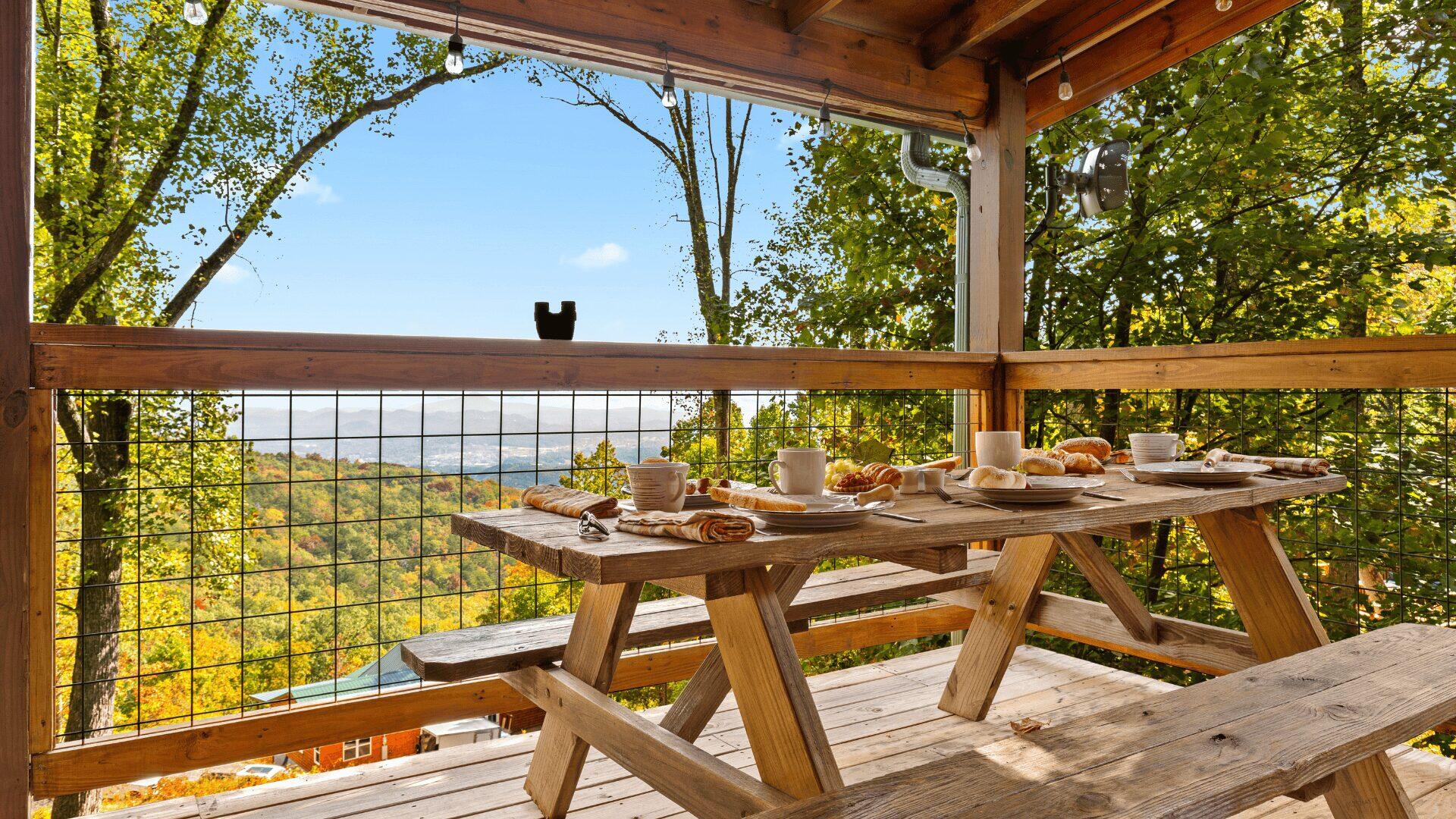 Places set for breakfast on a wooden bench on a balcony, with views across the valley.