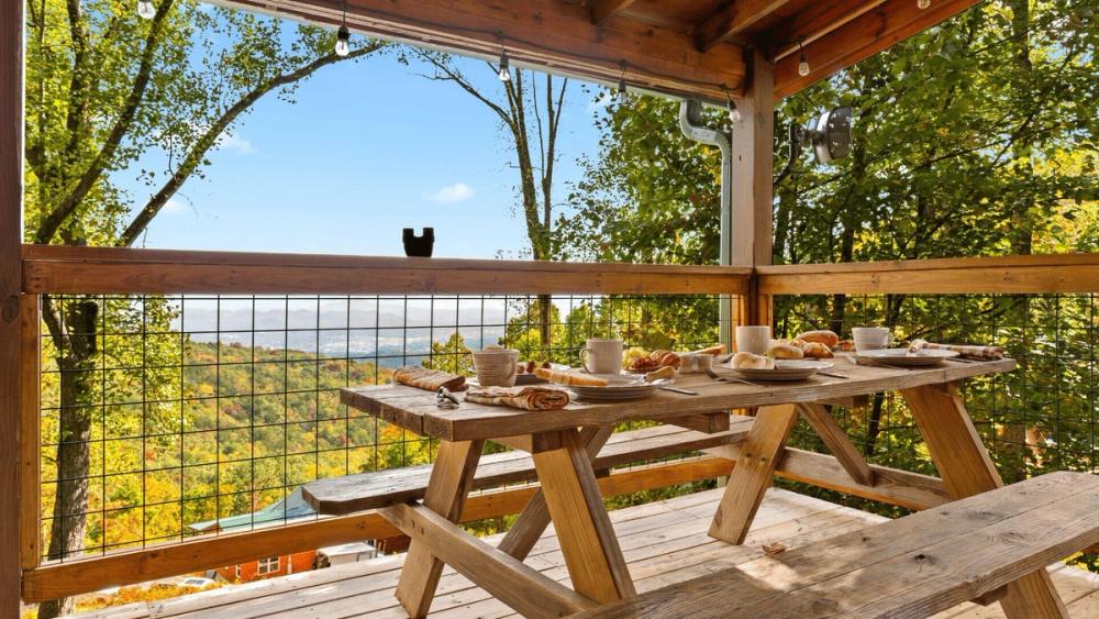 Places set for breakfast on a wooden bench on a balcony, with views across the valley.