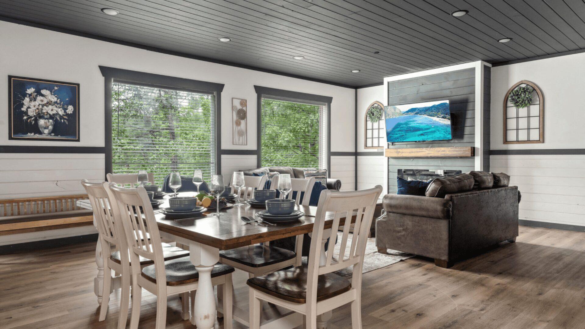 Wide shot of a living area, including dining table, two sofas and a wall mounted tv.