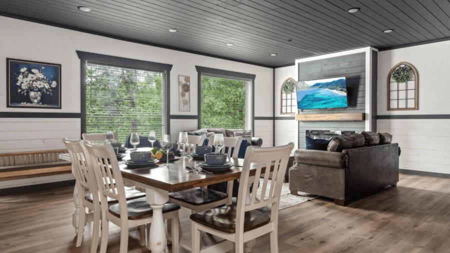 Wide shot of a living area, including dining table, two sofas and a wall mounted tv.