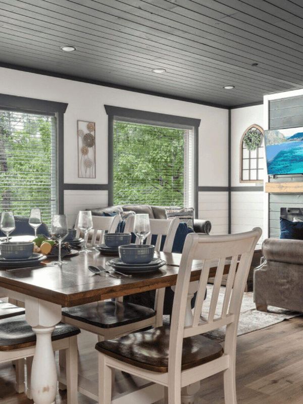 Wide shot of a living area, including dining table, two sofas and a wall mounted tv.