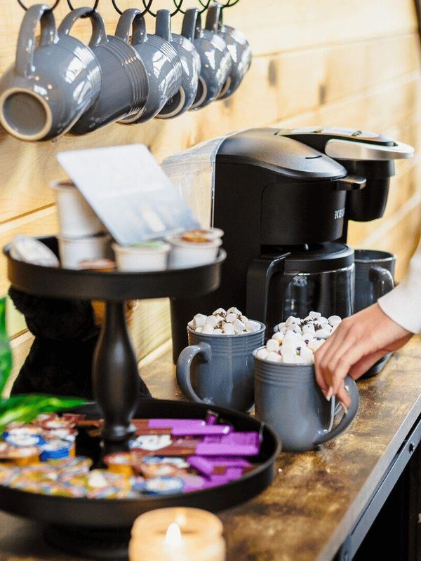A woman making hot chocolate next to a machine.