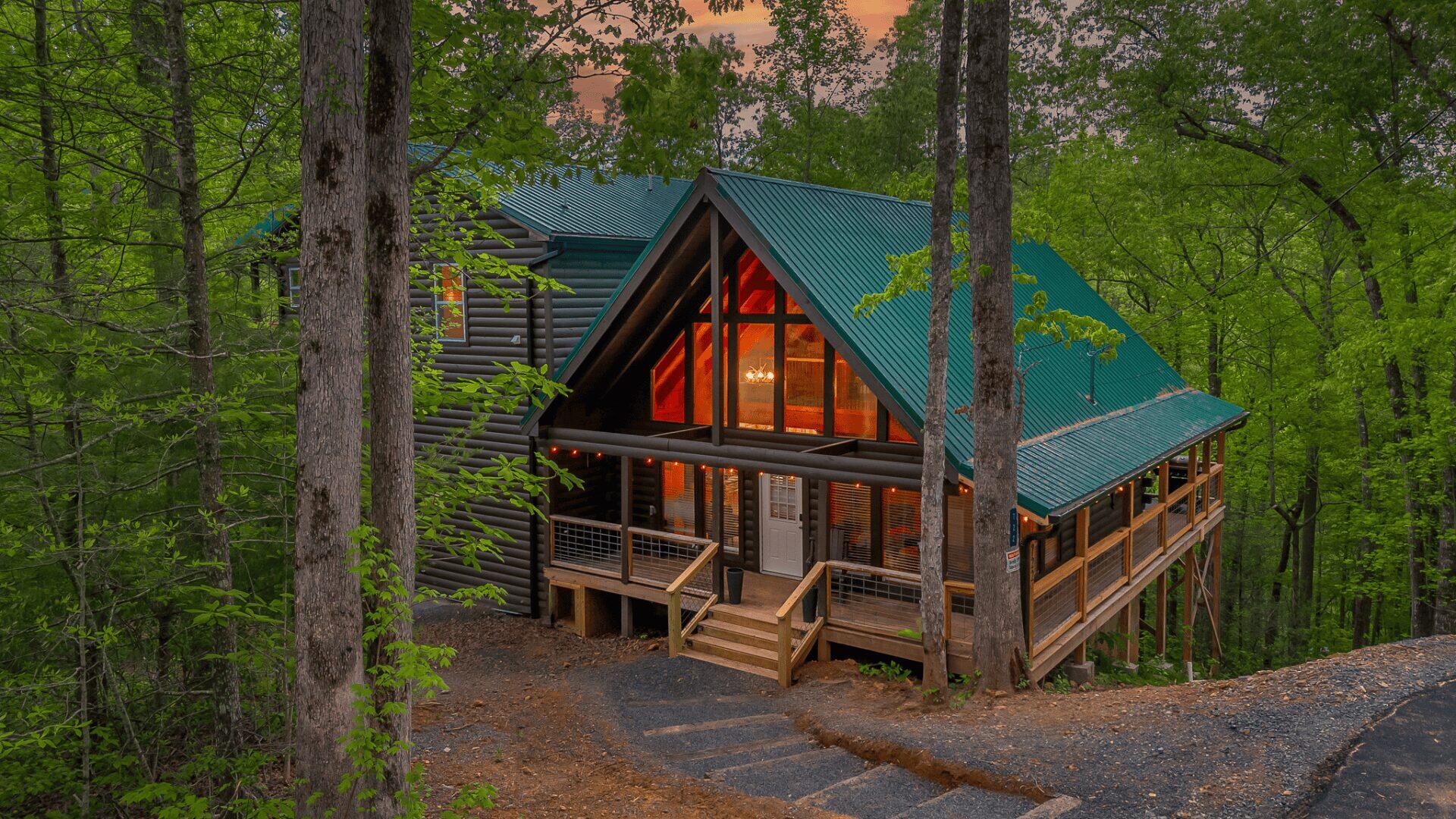 Stairs leading down to a large cabin in the woods. The cabin has large windows at the front of the property.