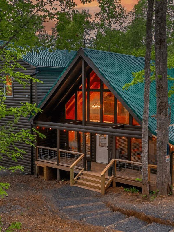 Stairs leading down to a large cabin in the woods. The cabin has large windows at the front of the property.