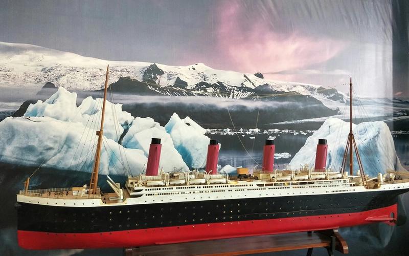 A large model of the Titanic ship is displayed at this popular Pigeon Forge attraction, set against a backdrop of icy waters, icebergs, and snow-covered mountains beneath a pink and purple sky—perfect for fans of the Titanic Museum.