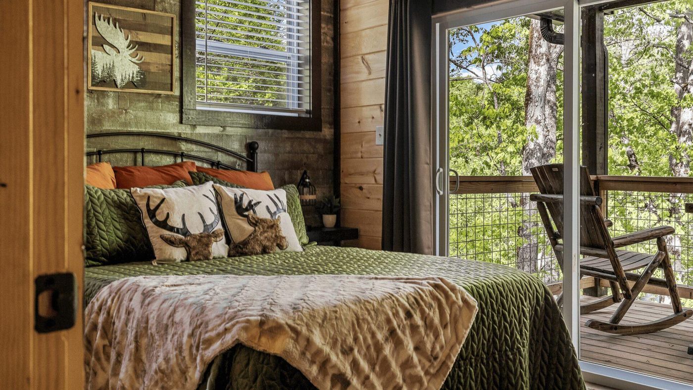A bed next to a sliding door. There is a balcony with a wooden rocking chair.
