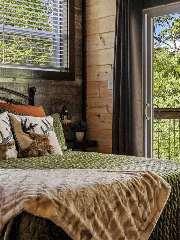 A bed next to a sliding door. There is a balcony with a wooden rocking chair.