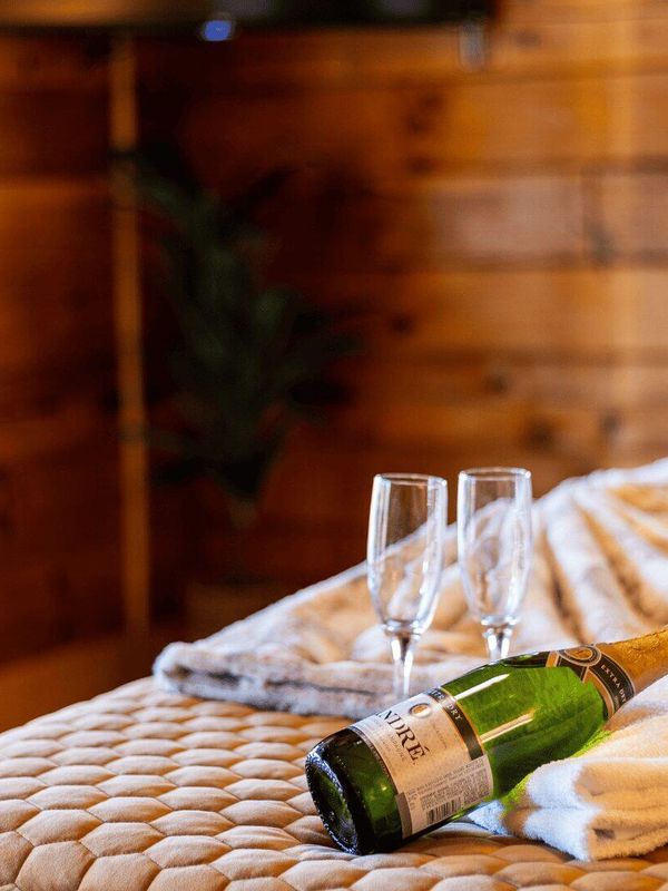 A bottle of champagne resting on a towel with two glasses beside it.