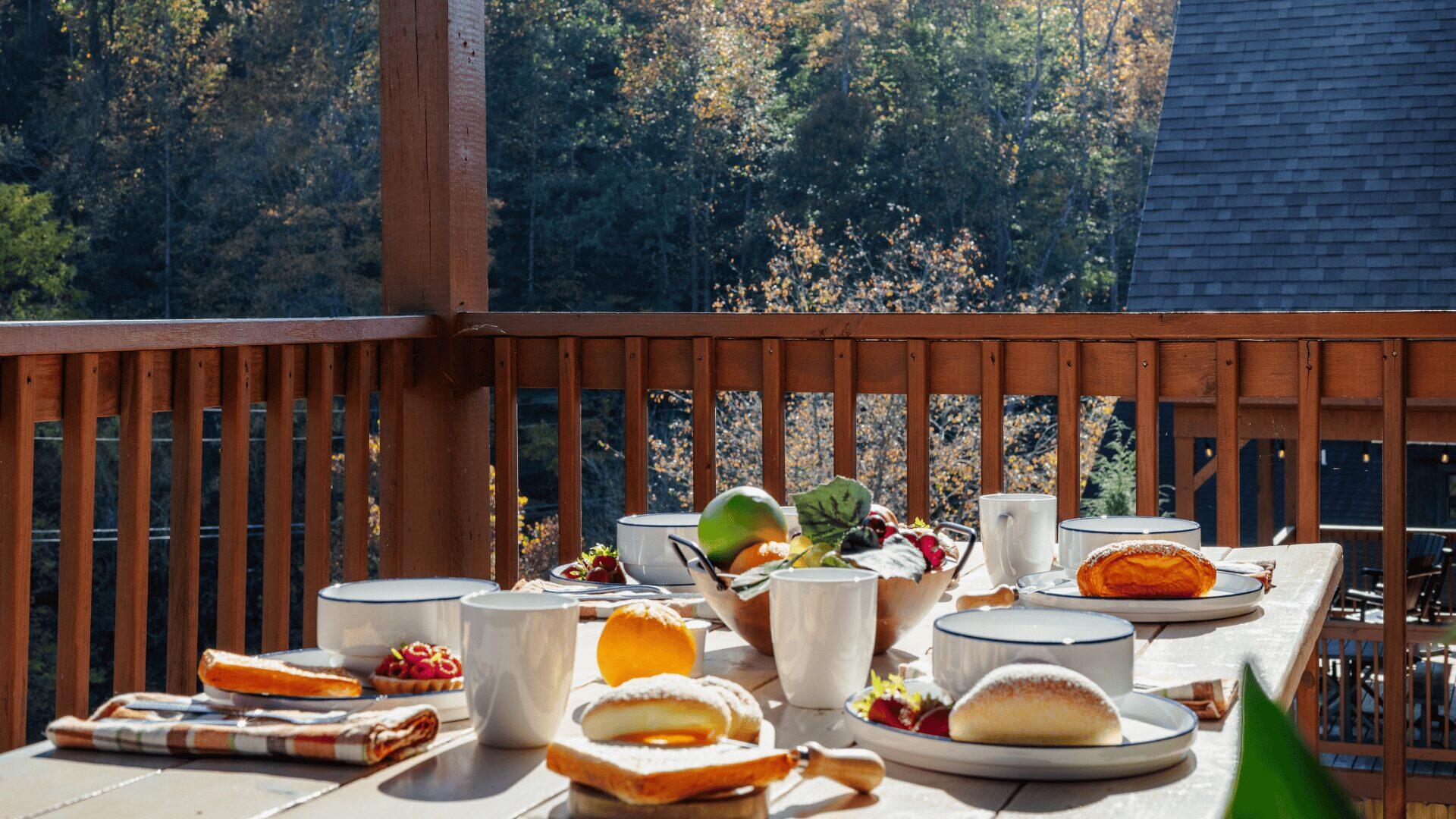 Four place settings for breakfast, including fresh fruit, at an outdoor table on a balcony.