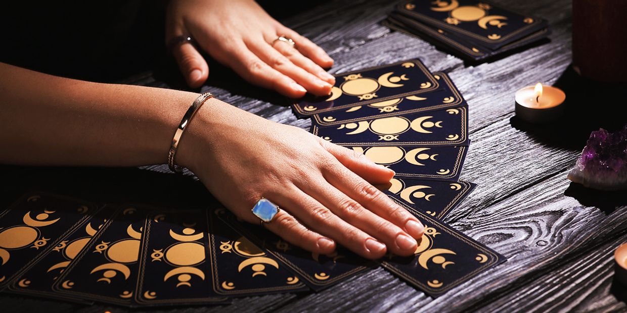 A psychic reader using a spread of tarot cards on a wooden table.