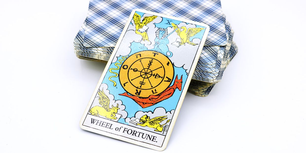 Wheel of Fortune tarot card on top of a deck of tarot cards, symbolising fate, turning points, and intuitive guidance.