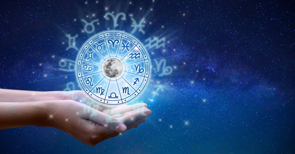 A horoscope chart balanced above a hand
