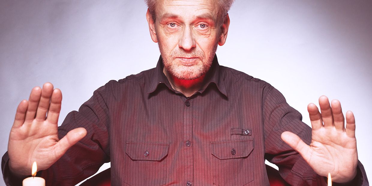 Mature male psychic with hands raised up in an energy reading ritual, symbolising spiritual healing, protection, and intuitive power.